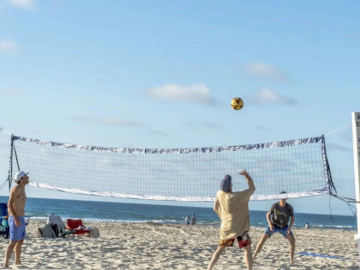 Group playing a game of beach volleyball by the sea on a sunny day