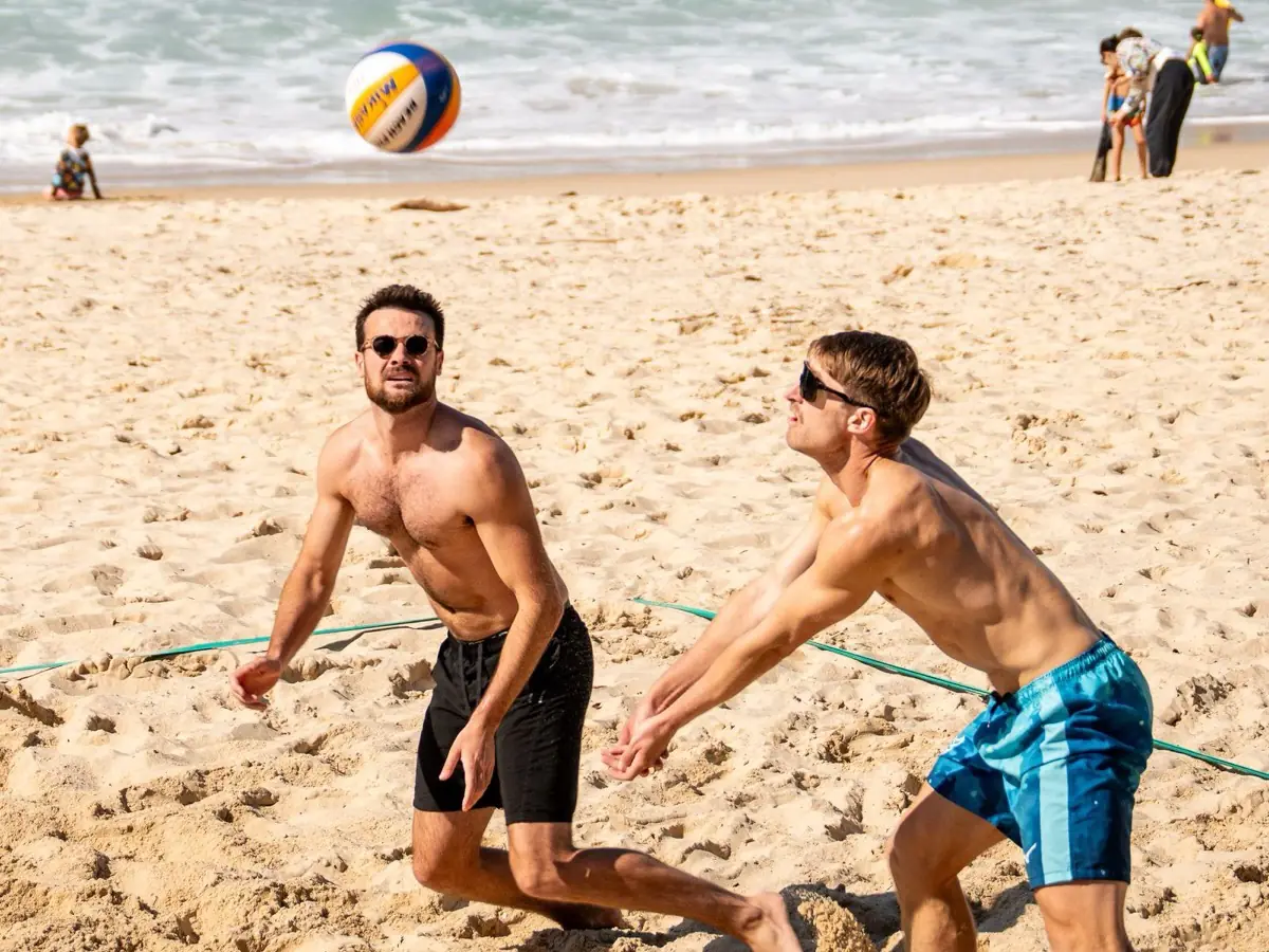 Two players on the sand, ready to receive a beach volleyball